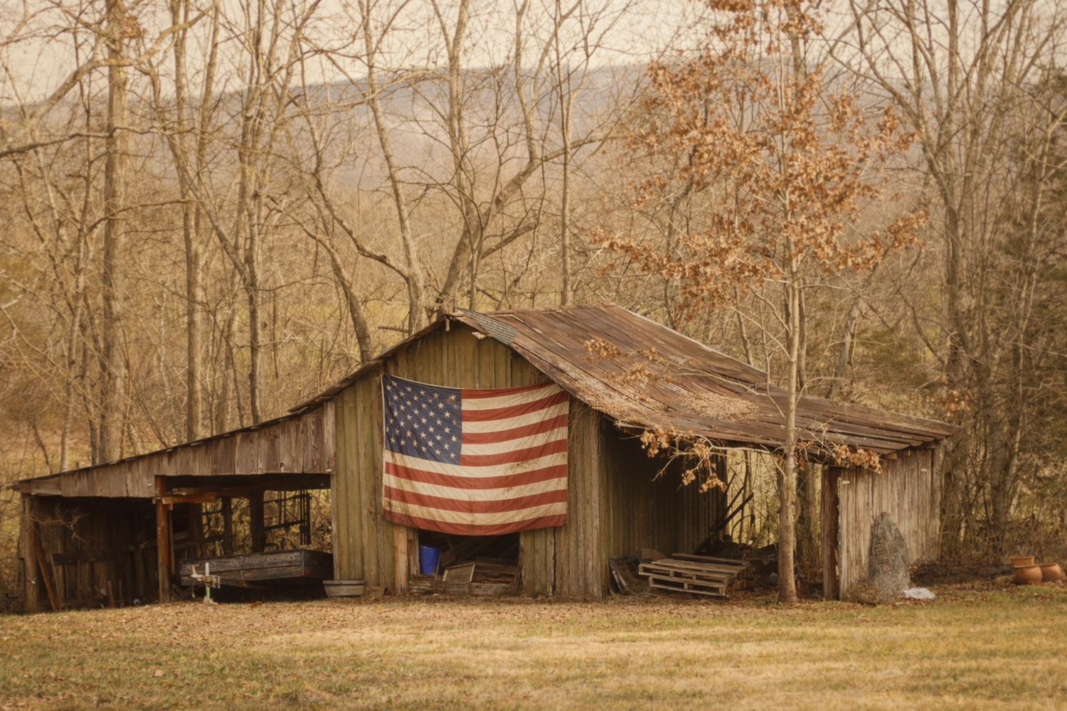 Rustic wooden barn with American flag hanging over the doorway in a rural setting, hero image for Legendary Redneck™ patriot-owned apparel brand.